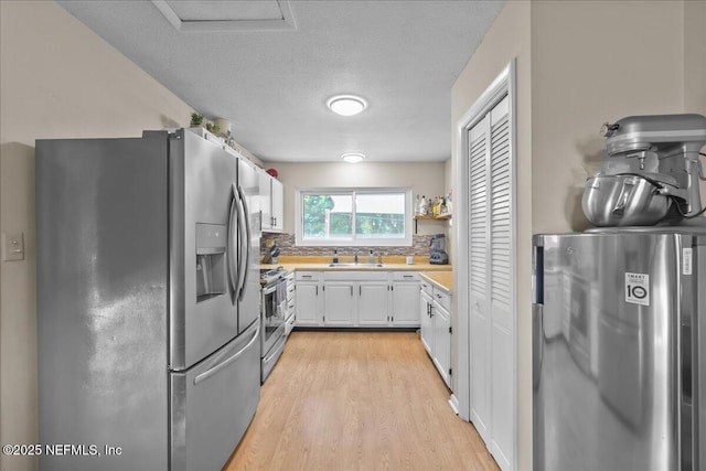 1331 Sheffield Rd, Saint Johns, FL 32259 - kitchen with stainless steel appliances, white cabinetry, light countertops, light wood finished floors, and backsplash