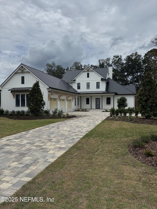 146 Whistling Palm Ct Lot 90, Ponte Vedra, FL 32081 - modern farmhouse style home featuring board and batten siding, a chimney, decorative driveway, a front lawn, and a metal roof