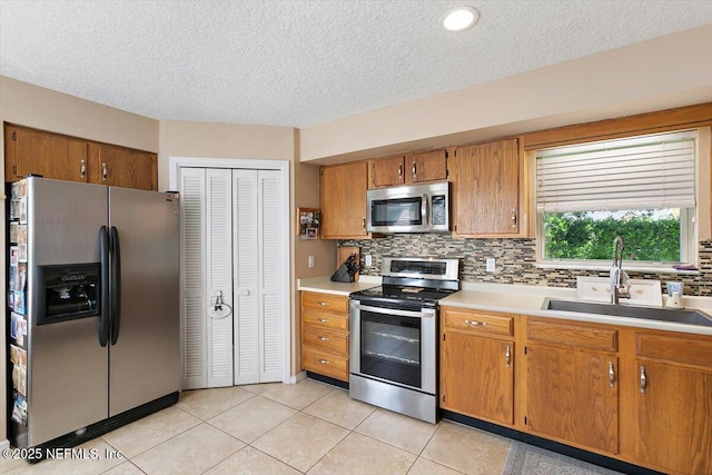 101 Duck Bill Cv, Ponte Vedra Beach, FL 32082 - kitchen featuring appliances with stainless steel finishes, a textured ceiling, brown cabinetry, light countertops, and backsplash