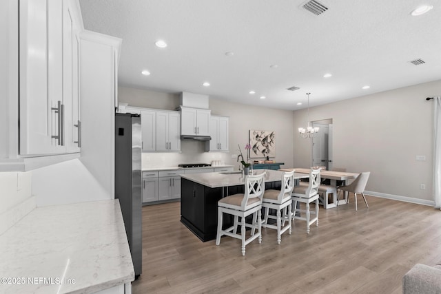 106 Rum Runner Way, Saint Johns, FL 32259 - kitchen with freestanding refrigerator, a kitchen island with sink, recessed lighting, a breakfast bar area, and black stovetop