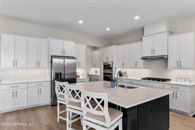 106 Rum Runner Way, Saint Johns, FL 32259 - kitchen with stainless steel appliances, white cabinetry, a center island with sink, light wood-style flooring, and a kitchen bar
