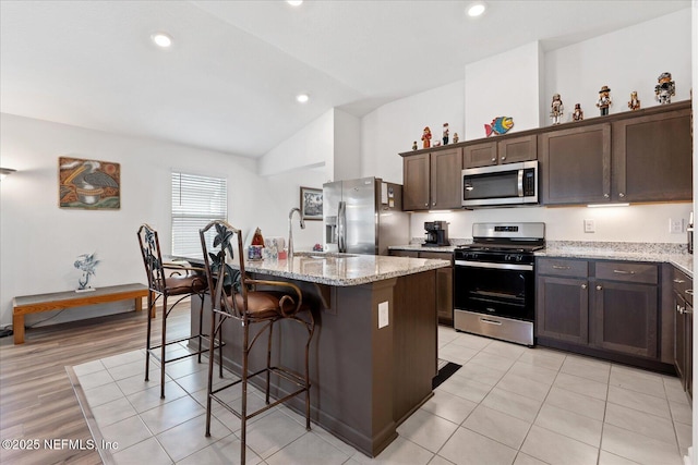 20 Willow St, Palm Coast, FL 32164 - kitchen featuring stainless steel appliances, vaulted ceiling, an island with sink, dark brown cabinets, and a breakfast bar