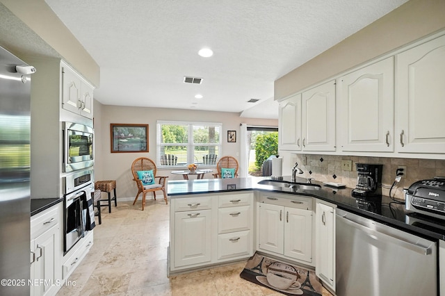4251 Monument Rd Unit 805, Jacksonville, FL 32225 - kitchen with appliances with stainless steel finishes, a peninsula, white cabinetry, dark countertops, and recessed lighting