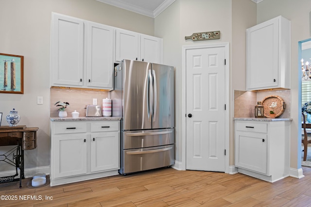 96740 Quartz Ln, Yulee, FL 32097 - kitchen with freestanding refrigerator, crown molding, white cabinetry, and tasteful backsplash