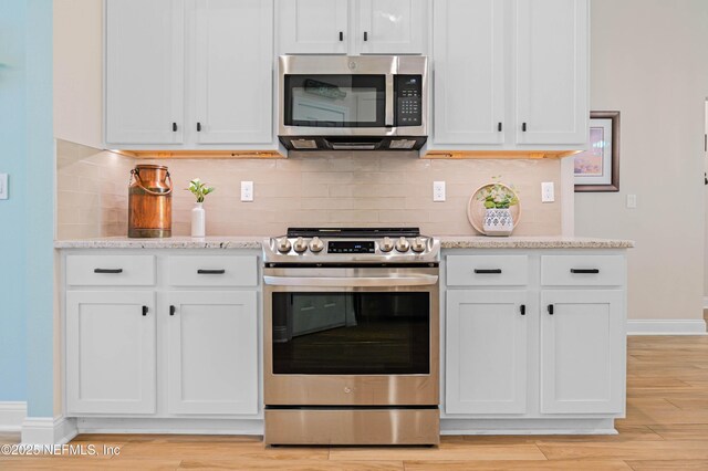 96740 Quartz Ln, Yulee, FL 32097 - kitchen featuring stainless steel appliances, decorative backsplash, light wood-style floors, and white cabinetry