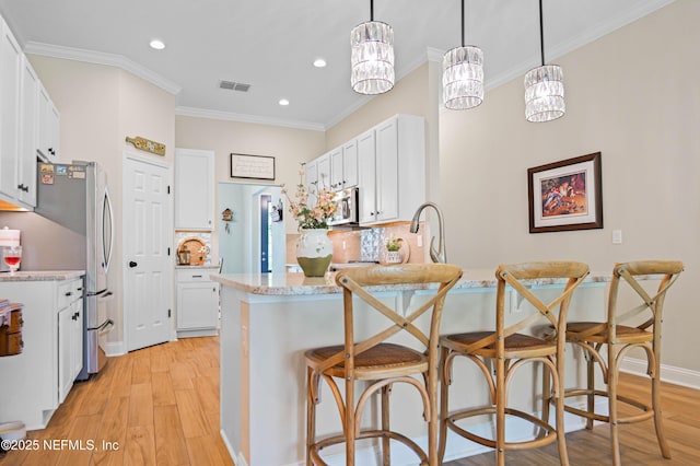 96740 Quartz Ln, Yulee, FL 32097 - kitchen featuring appliances with stainless steel finishes, a peninsula, light wood finished floors, a breakfast bar area, and crown molding