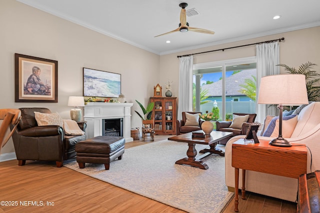 96740 Quartz Ln, Yulee, FL 32097 - living room featuring light wood-style floors, crown molding, recessed lighting, a ceiling fan, and a fireplace with raised hearth