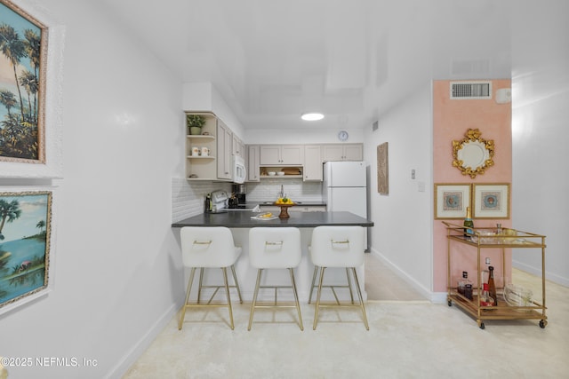 1071 Edgewood Ave S Unit 407, Jacksonville, FL 32205 - kitchen featuring open shelves, dark countertops, a peninsula, decorative backsplash, and a kitchen bar