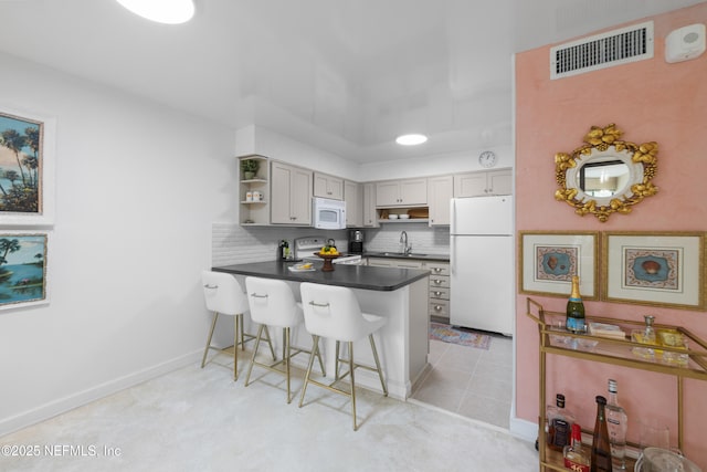 1071 Edgewood Ave S Unit 407, Jacksonville, FL 32205 - kitchen featuring white appliances, a peninsula, dark countertops, open shelves, and a breakfast bar area