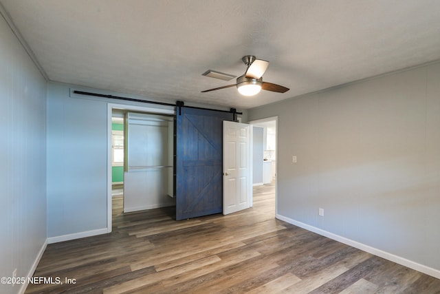 5299 County Road 352nd Rd, Keystone Heights, FL 32656 - unfurnished bedroom featuring wood finished floors, a ceiling fan, and a barn door