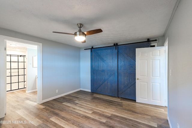 5299 County Road 352nd Rd, Keystone Heights, FL 32656 - unfurnished bedroom with a barn door, wood finished floors, and a ceiling fan