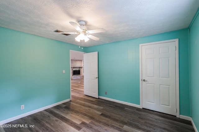 5299 County Road 352nd Rd, Keystone Heights, FL 32656 - unfurnished bedroom with dark wood-style flooring, a fireplace, a textured ceiling, and ceiling fan