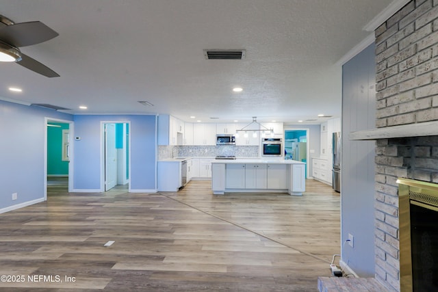 5299 County Road 352nd Rd, Keystone Heights, FL 32656 - kitchen featuring stainless steel appliances, a brick fireplace, light countertops, white cabinets, and open floor plan