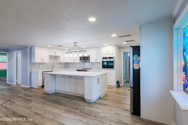5299 County Road 352nd Rd, Keystone Heights, FL 32656 - kitchen featuring appliances with stainless steel finishes, white cabinets, light countertops, tasteful backsplash, and light wood-style floors