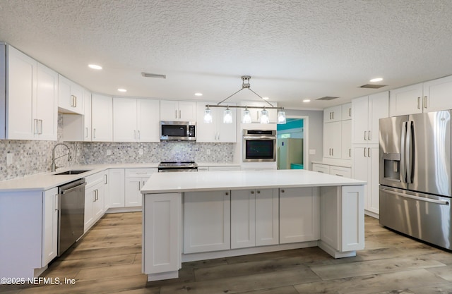 5299 County Road 352nd Rd, Keystone Heights, FL 32656 - kitchen featuring stainless steel appliances, a center island, wood finished floors, a textured ceiling, and light countertops
