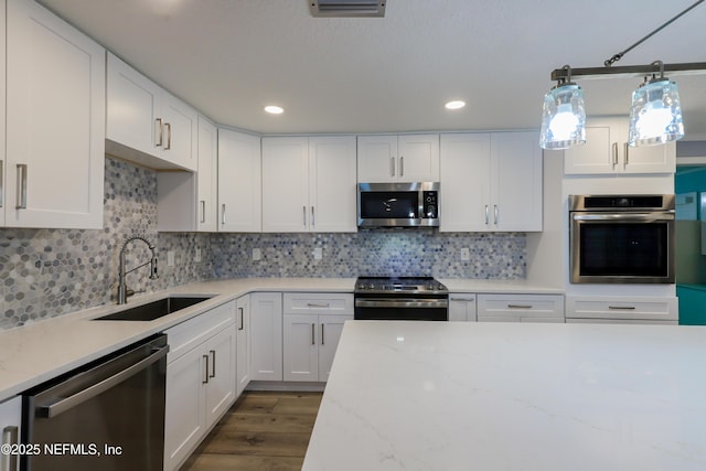 5299 County Road 352nd Rd, Keystone Heights, FL 32656 - kitchen featuring appliances with stainless steel finishes, dark wood-style floors, white cabinetry, tasteful backsplash, and light stone counters