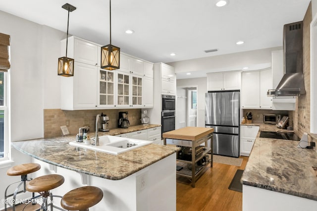 1805 Commodore Point Dr, Fleming Island, FL 32003 - kitchen with black appliances, wall chimney range hood, a peninsula, white cabinets, and a breakfast bar area