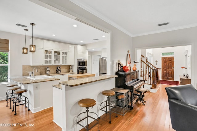 1805 Commodore Point Dr, Fleming Island, FL 32003 - kitchen featuring a peninsula, a breakfast bar area, appliances with stainless steel finishes, light wood finished floors, and white cabinets
