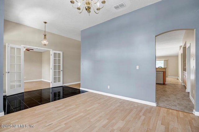 1069 Ardmore St, Saint Augustine, FL 32092 - empty room featuring french doors, arched walkways, wood finished floors, and a chandelier
