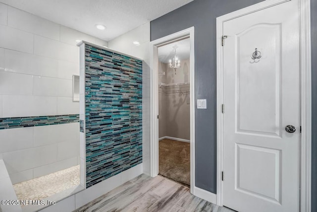 1069 Ardmore St, Saint Augustine, FL 32092 - bathroom featuring a chandelier, wood finished floors, a spacious closet, tiled shower, and a textured ceiling
