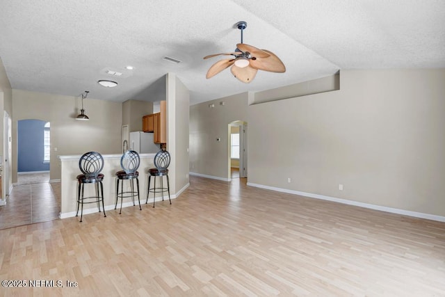 1069 Ardmore St, Saint Augustine, FL 32092 - kitchen featuring arched walkways, freestanding refrigerator, ceiling fan, a textured ceiling, and a breakfast bar