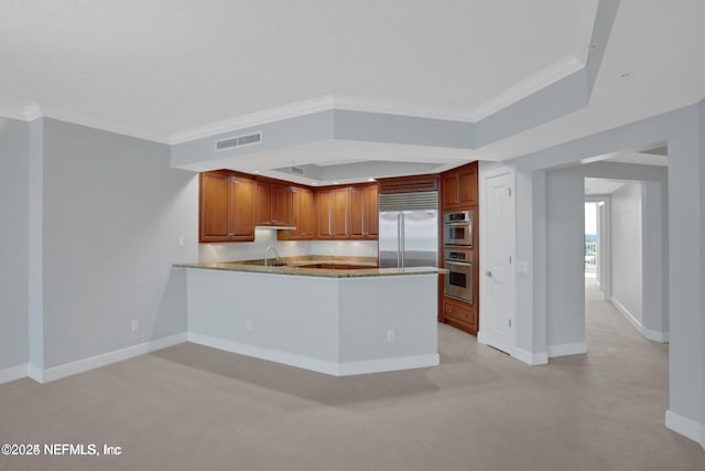1031 1st St S Unit 504, Jacksonville Beach, FL 32250 - kitchen with appliances with stainless steel finishes, crown molding, a peninsula, brown cabinets, and under cabinet range hood