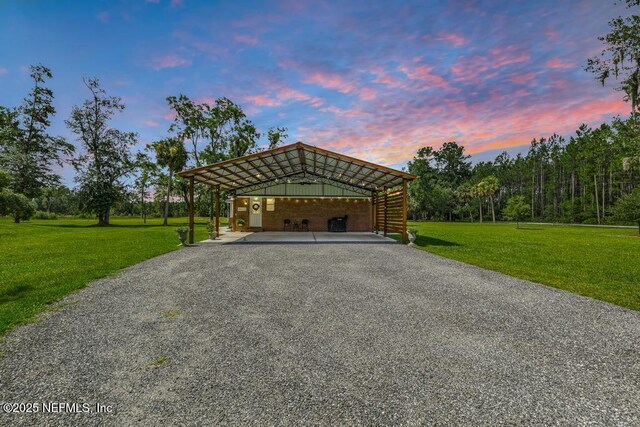 26122 Sheared Stokes Rd, Hilliard, FL 32046 - garage at dusk with a carport, a lawn, and gravel driveway