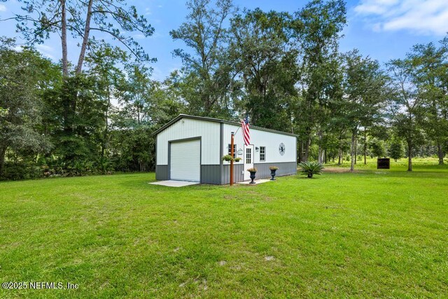 26122 Sheared Stokes Rd, Hilliard, FL 32046 - view of grassy yard featuring an outdoor structure, a detached garage, and view of wooded area