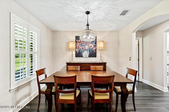 26122 Sheared Stokes Rd, Hilliard, FL 32046 - dining room with arched walkways, dark wood-style flooring, a chandelier, and a textured ceiling