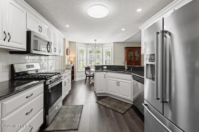 26122 Sheared Stokes Rd, Hilliard, FL 32046 - kitchen featuring stainless steel appliances, a peninsula, a textured ceiling, white cabinetry, and decorative backsplash