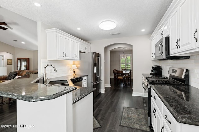 26122 Sheared Stokes Rd, Hilliard, FL 32046 - kitchen with stainless steel appliances, arched walkways, a peninsula, white cabinets, and backsplash