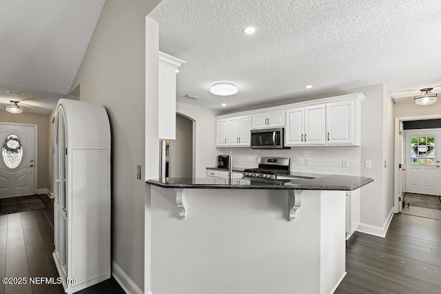 26122 Sheared Stokes Rd, Hilliard, FL 32046 - kitchen featuring appliances with stainless steel finishes, a kitchen breakfast bar, white cabinetry, backsplash, and a peninsula