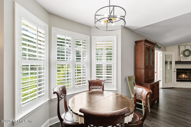 26122 Sheared Stokes Rd, Hilliard, FL 32046 - dining space featuring a chandelier, plenty of natural light, a warm lit fireplace, and dark wood-style floors