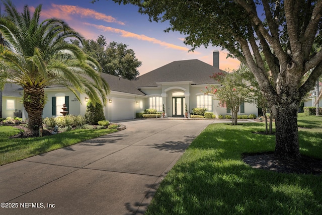 1317 Garrison Dr, Saint Augustine, FL 32092 - view of front of home with driveway, an attached garage, stucco siding, a chimney, and a yard