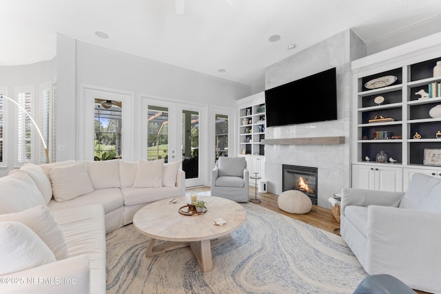 1317 Garrison Dr, Saint Augustine, FL 32092 - living room featuring a glass covered fireplace, wood finished floors, built in shelves, and french doors