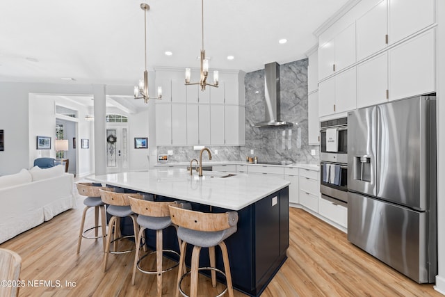 1317 Garrison Dr, Saint Augustine, FL 32092 - kitchen featuring stainless steel appliances, wall chimney range hood, backsplash, light wood-type flooring, and a kitchen bar