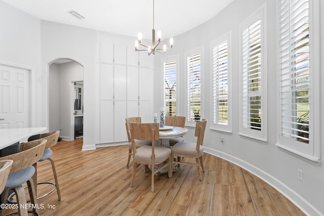 1317 Garrison Dr, Saint Augustine, FL 32092 - dining area featuring arched walkways, light wood-type flooring, and a chandelier