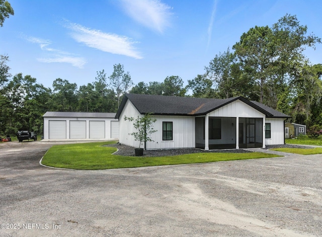 432 SE 55th St, Keystone Heights, FL 32656 - view of front of property featuring a garage, a sunroom, an outdoor structure, a front lawn, and dirt driveway