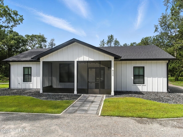 432 SE 55th St, Keystone Heights, FL 32656 - modern farmhouse featuring a sunroom, board and batten siding, roof with shingles, and a front yard