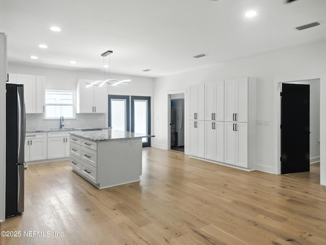 432 SE 55th St, Keystone Heights, FL 32656 - kitchen featuring freestanding refrigerator, a center island, white cabinetry, light wood-style flooring, and recessed lighting