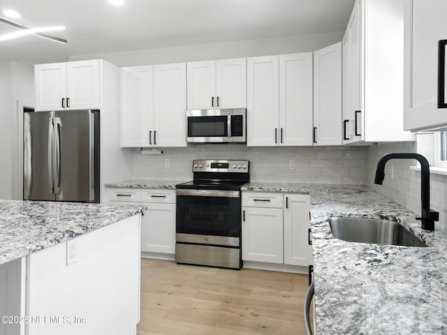 432 SE 55th St, Keystone Heights, FL 32656 - kitchen with appliances with stainless steel finishes, white cabinetry, light wood-type flooring, and tasteful backsplash