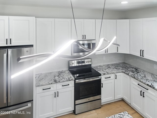 432 SE 55th St, Keystone Heights, FL 32656 - kitchen with appliances with stainless steel finishes, white cabinetry, light wood-type flooring, and light stone counters