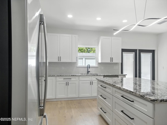 432 SE 55th St, Keystone Heights, FL 32656 - kitchen featuring freestanding refrigerator, light wood finished floors, backsplash, white cabinets, and recessed lighting