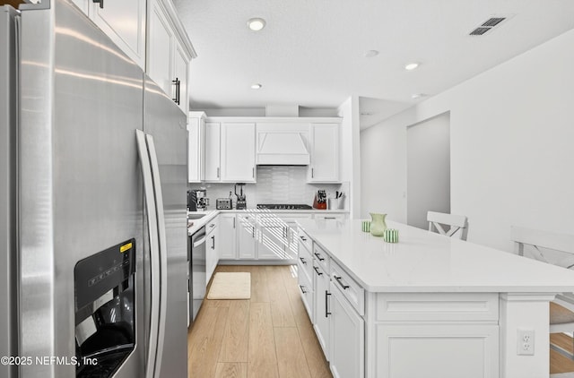 322 Fairlake Cir, Saint Augustine, FL 32092 - kitchen featuring appliances with stainless steel finishes, custom range hood, light wood finished floors, a center island, and recessed lighting