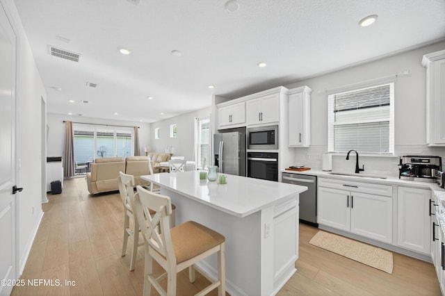 322 Fairlake Cir, Saint Augustine, FL 32092 - kitchen featuring appliances with stainless steel finishes, open floor plan, a center island, white cabinetry, and light wood-style floors