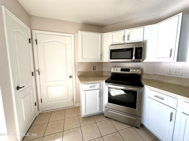 45575 Ingleham Cir, Callahan, FL 32011 - kitchen with stainless steel appliances, white cabinetry, light tile patterned flooring, light countertops, and a textured ceiling