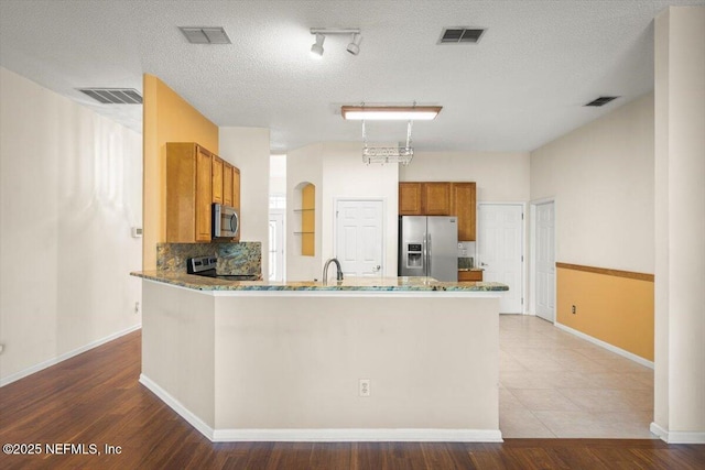 1385 Soaring Flight Way, Jacksonville, FL 32225 - kitchen featuring appliances with stainless steel finishes, a peninsula, brown cabinets, stone counters, and backsplash