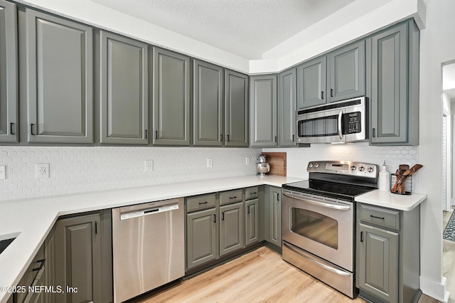 4342 Richmond Park Dr E, Jacksonville, FL 32224 - kitchen with stainless steel appliances, gray cabinets, decorative backsplash, light wood-style flooring, and a textured ceiling