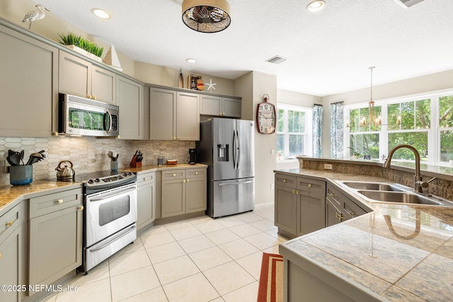 308 High Tide Dr Unit 201, Saint Augustine, FL 32080 - kitchen featuring stainless steel appliances, gray cabinets, decorative backsplash, hanging light fixtures, and light tile patterned floors