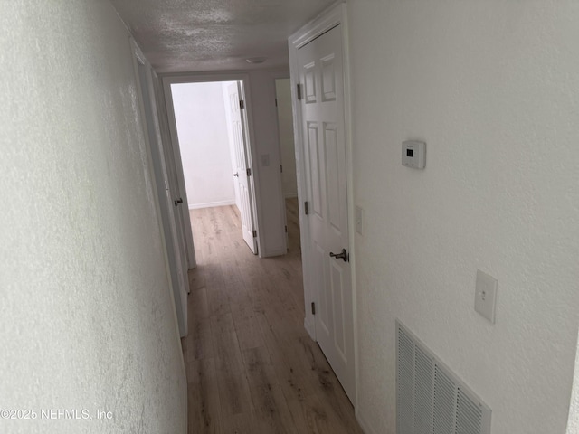 7942 Helston Dr, Jacksonville, FL 32208 - hallway featuring light wood-style flooring, a textured ceiling, and a textured wall
